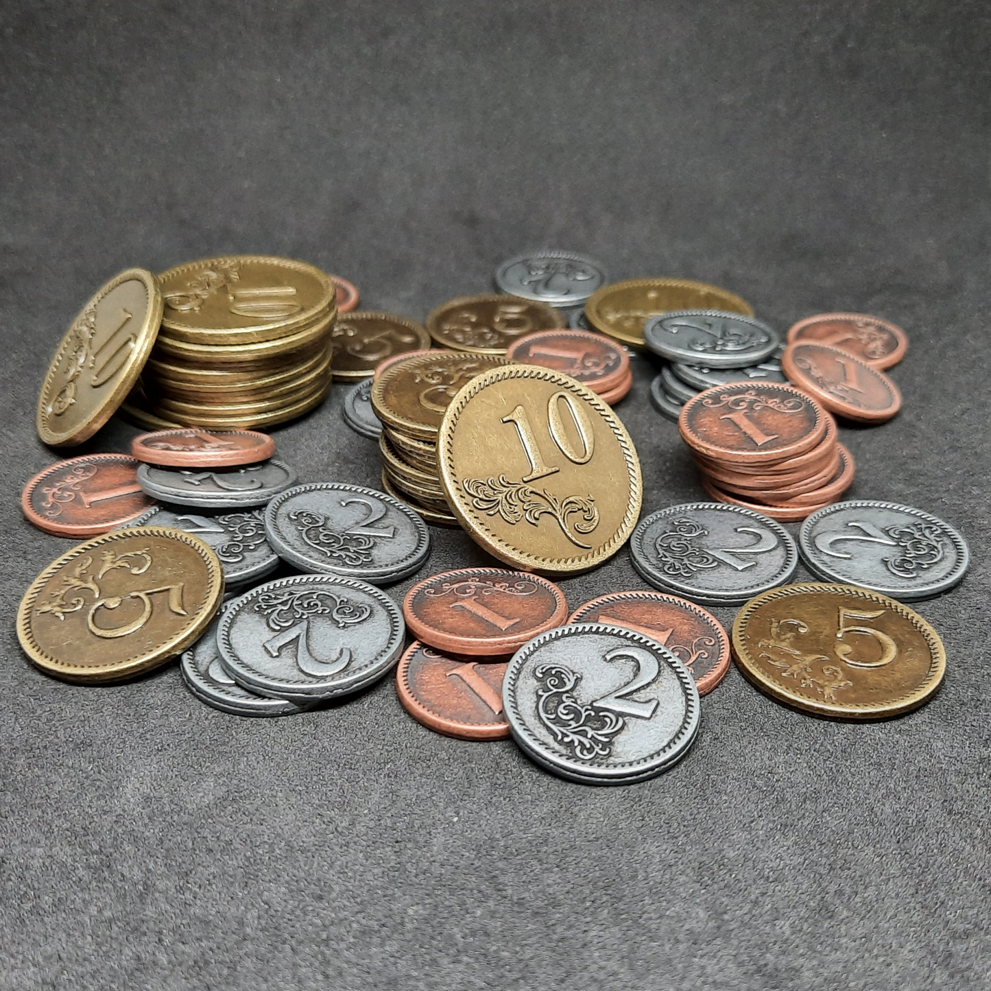 Set of bronze, silver and gold metal coins of value 1, 2, 5 and 10 for board games