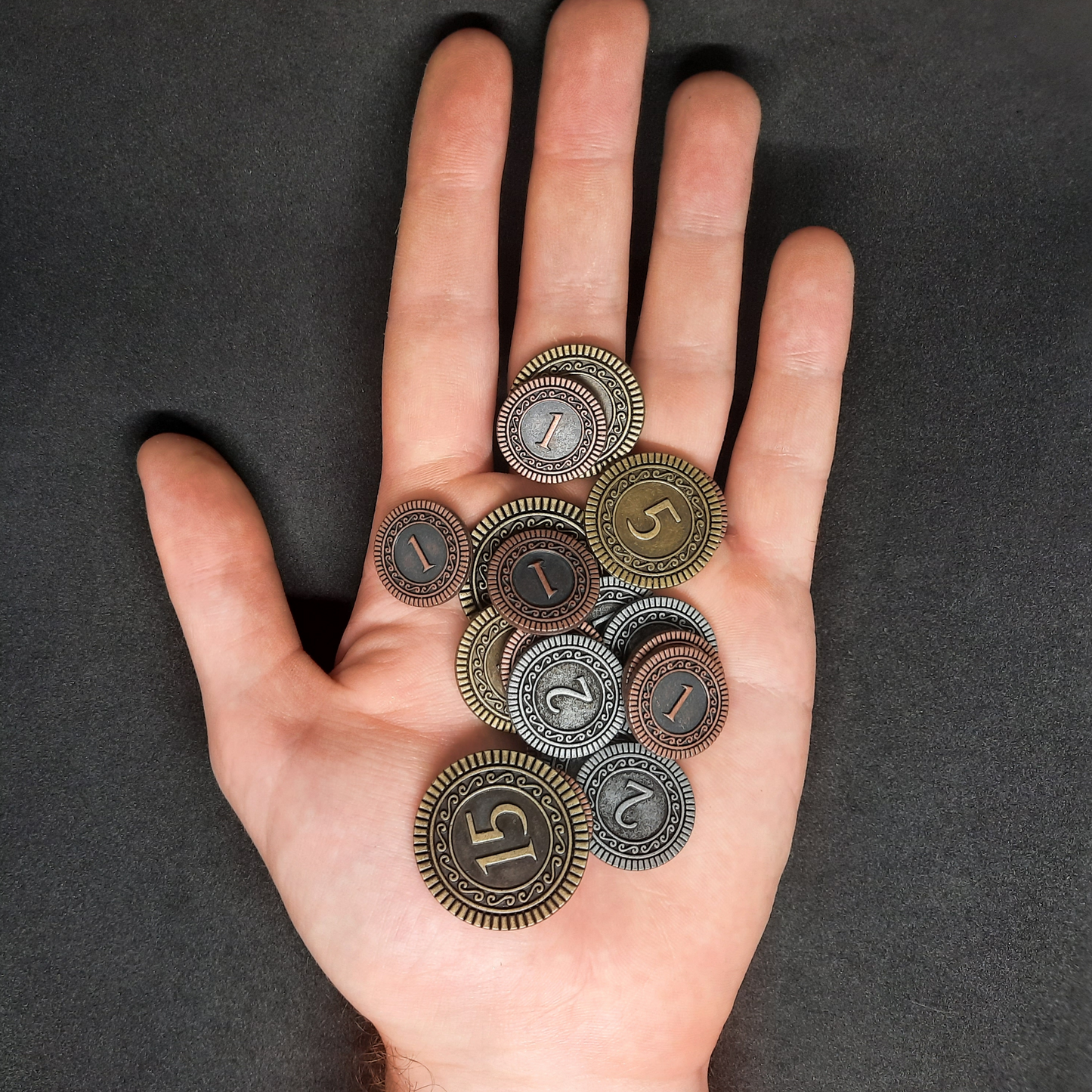 Set of bronze, silver and gold metal coins of value 1, 2, 5 and 15 for board games