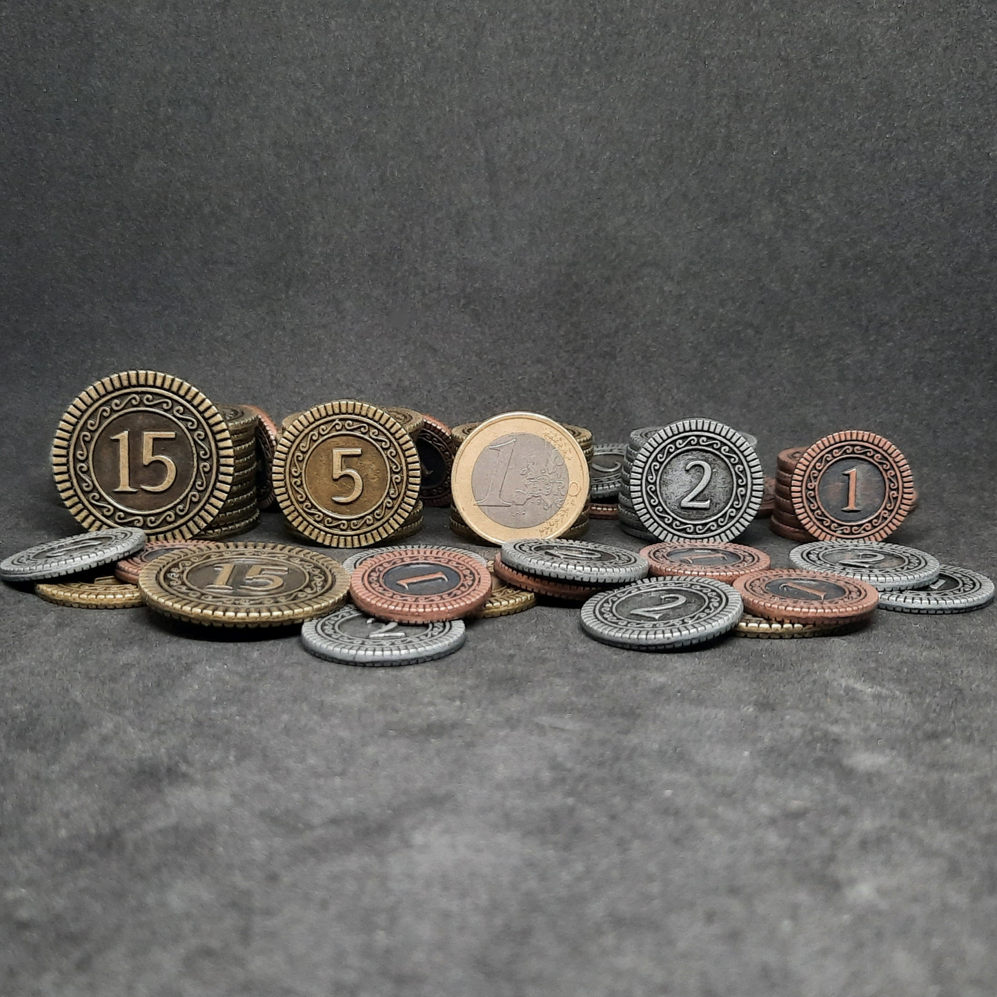 Set of bronze, silver and gold metal coins of value 1, 2, 5 and 15 for board games