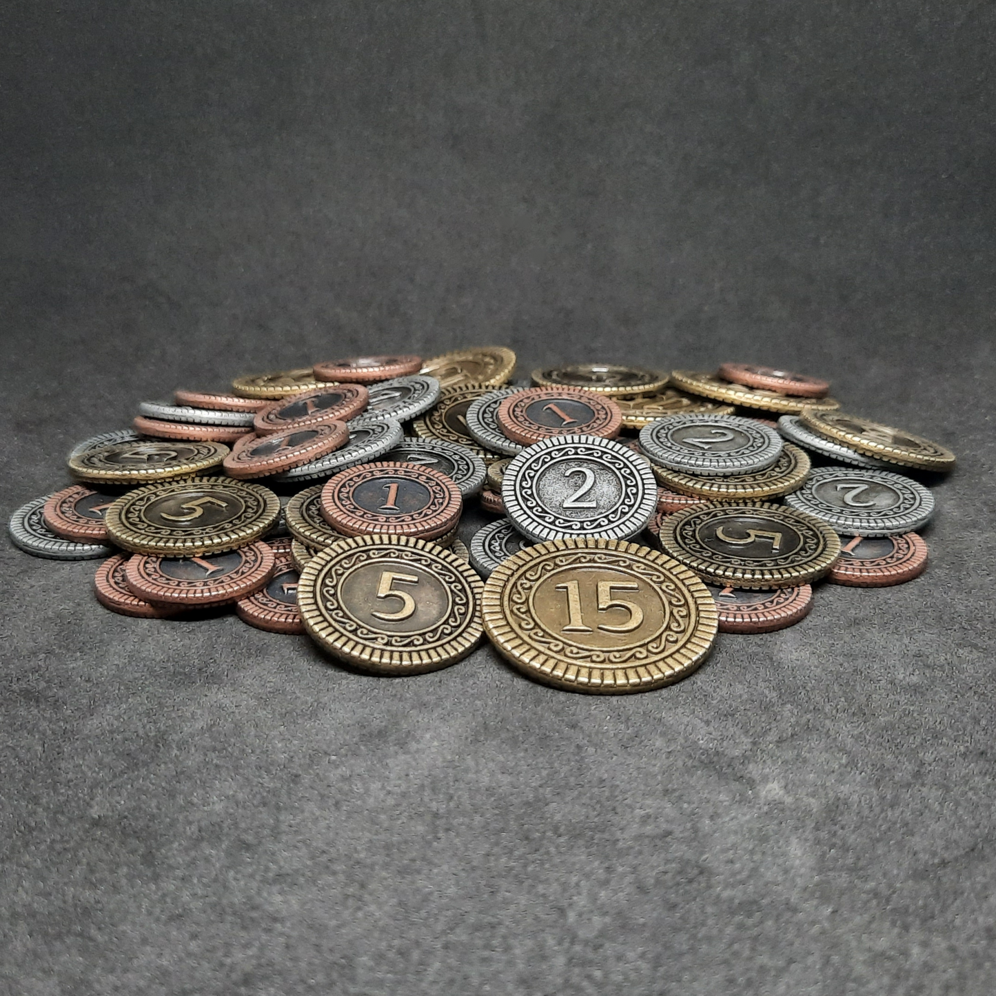 Set of bronze, silver and gold metal coins of value 1, 2, 5 and 15 for board games